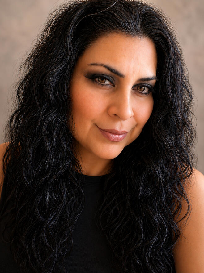 Headshot of Lesley Silva-Kopec with long dark curly hair, wearing a black sleeveless top and smiling at the camera.
